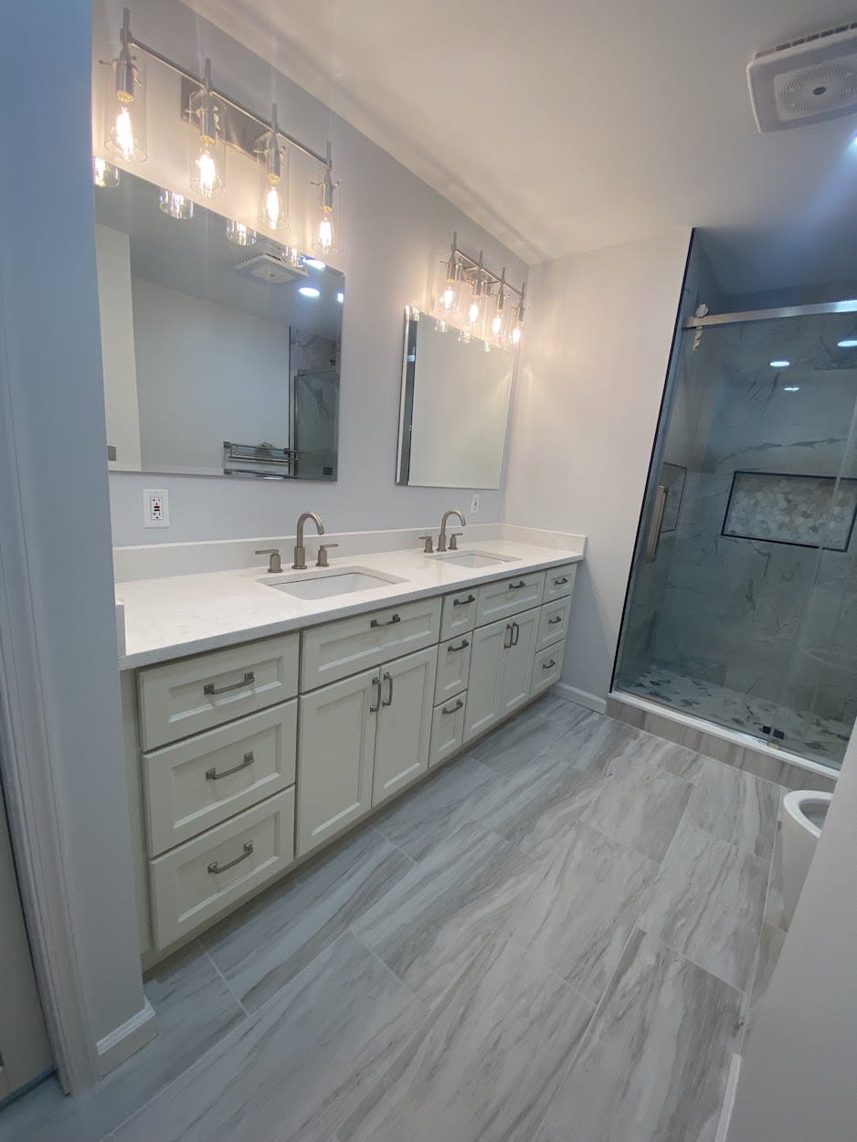 Bathroom with a double vanity, quartz counters, and a glass shower