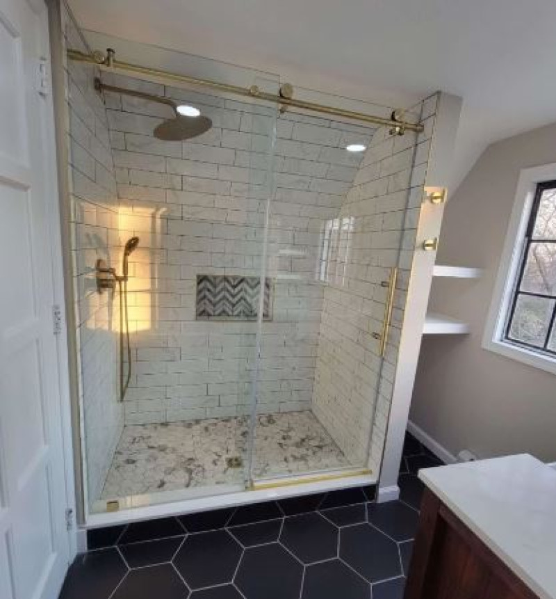 Walk-in shower with teal tile and a dark double vanity