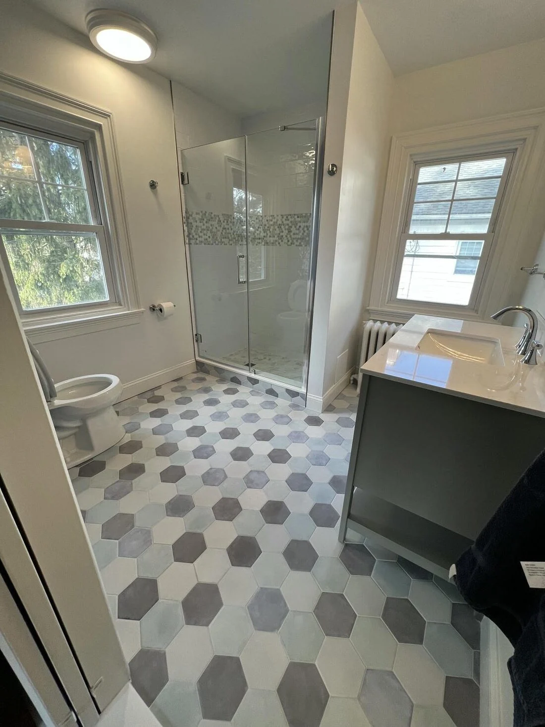 Teal tiled walk-in shower beside a dark vanity